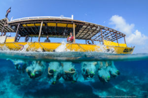 Gili Divers back rolling off a bright yellow boat into crystal clear blue water